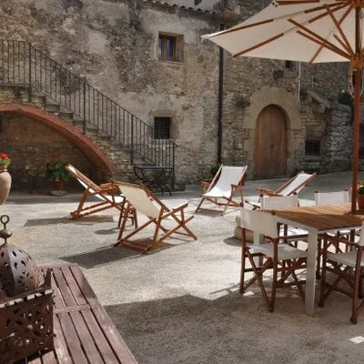 Chiliennes et salon de jardin sous parasol dans la cour d'un hôtel