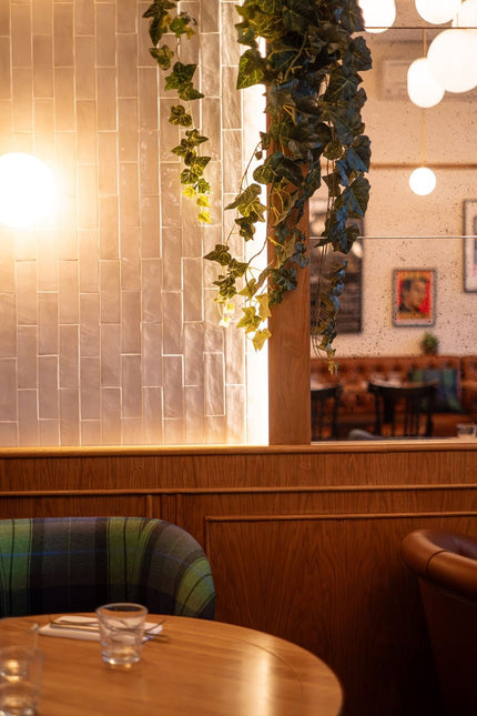 Aménagement de restaurant professionnel avec table ronde, banquette et décoration végétale