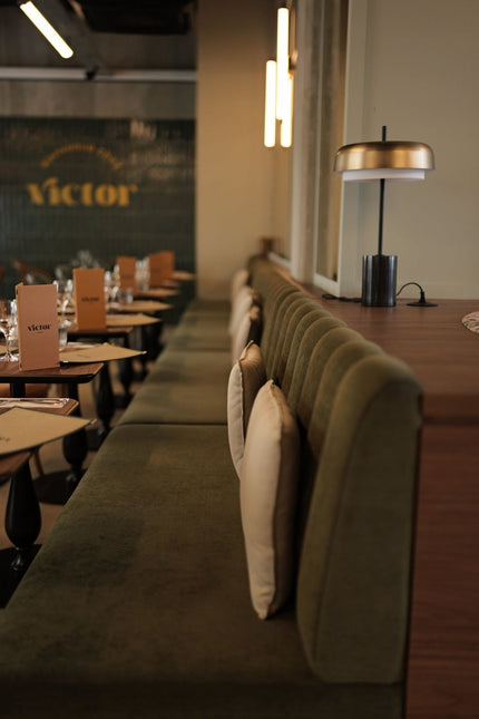 Projet Victor - banquette de restaurant verte avec tables dressées et éclairage mural