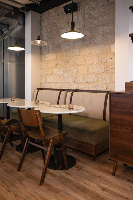 Aménagement de restaurant professionnel avec banquette verte, table ronde et mur en pierre