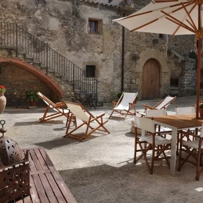Chiliennes et salon de jardin sous parasol dans la cour d'un hôtel