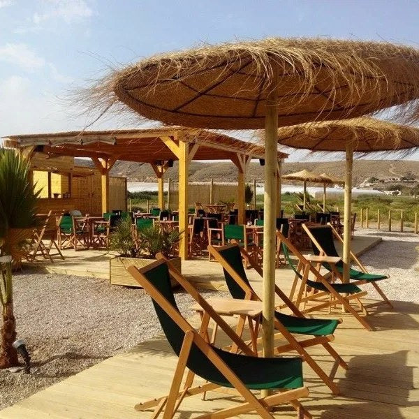 Chiliennes en bois sous paillotes sur la terrasse d'un beach bar